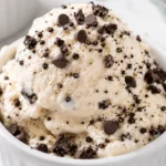 Cottage cheese ice cream scooped into a white ramekin with chocolate chips and cookie crumbs, made as a creamy high-protein no-machine dessert.