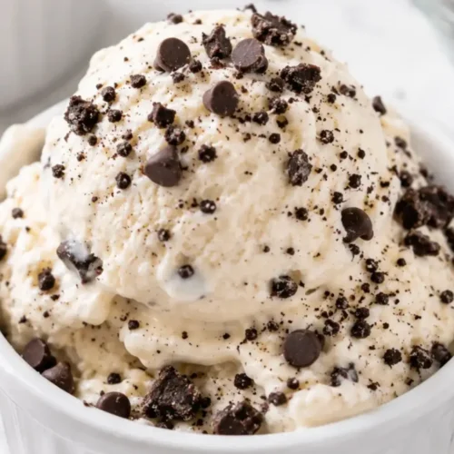 Cottage cheese ice cream scooped into a white ramekin with chocolate chips and cookie crumbs, made as a creamy high-protein no-machine dessert.
