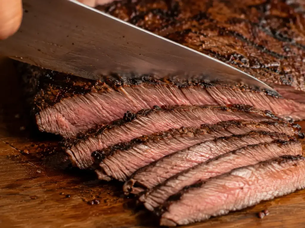 Slicing marinated steak thinly against the grain with a knife