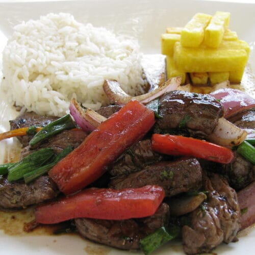 Lomo saltado, a Peruvian beef stir-fry with onion, tomato, and fries, served over rice
