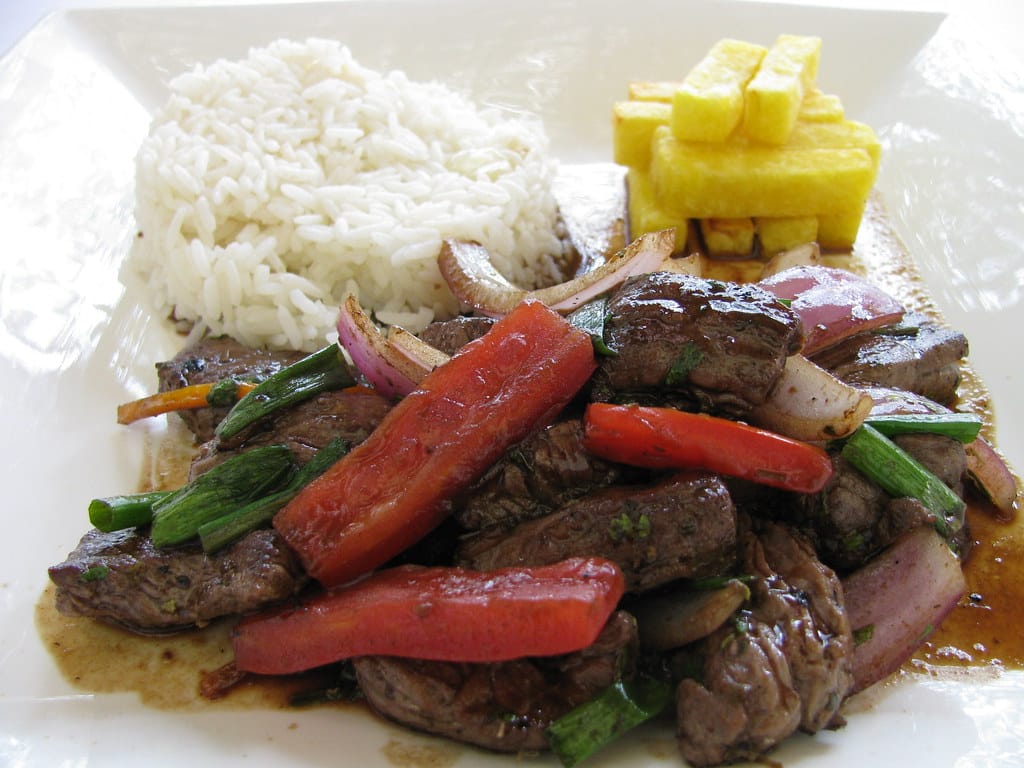 Lomo saltado, a Peruvian beef stir-fry with onion, tomato, and fries, served over rice