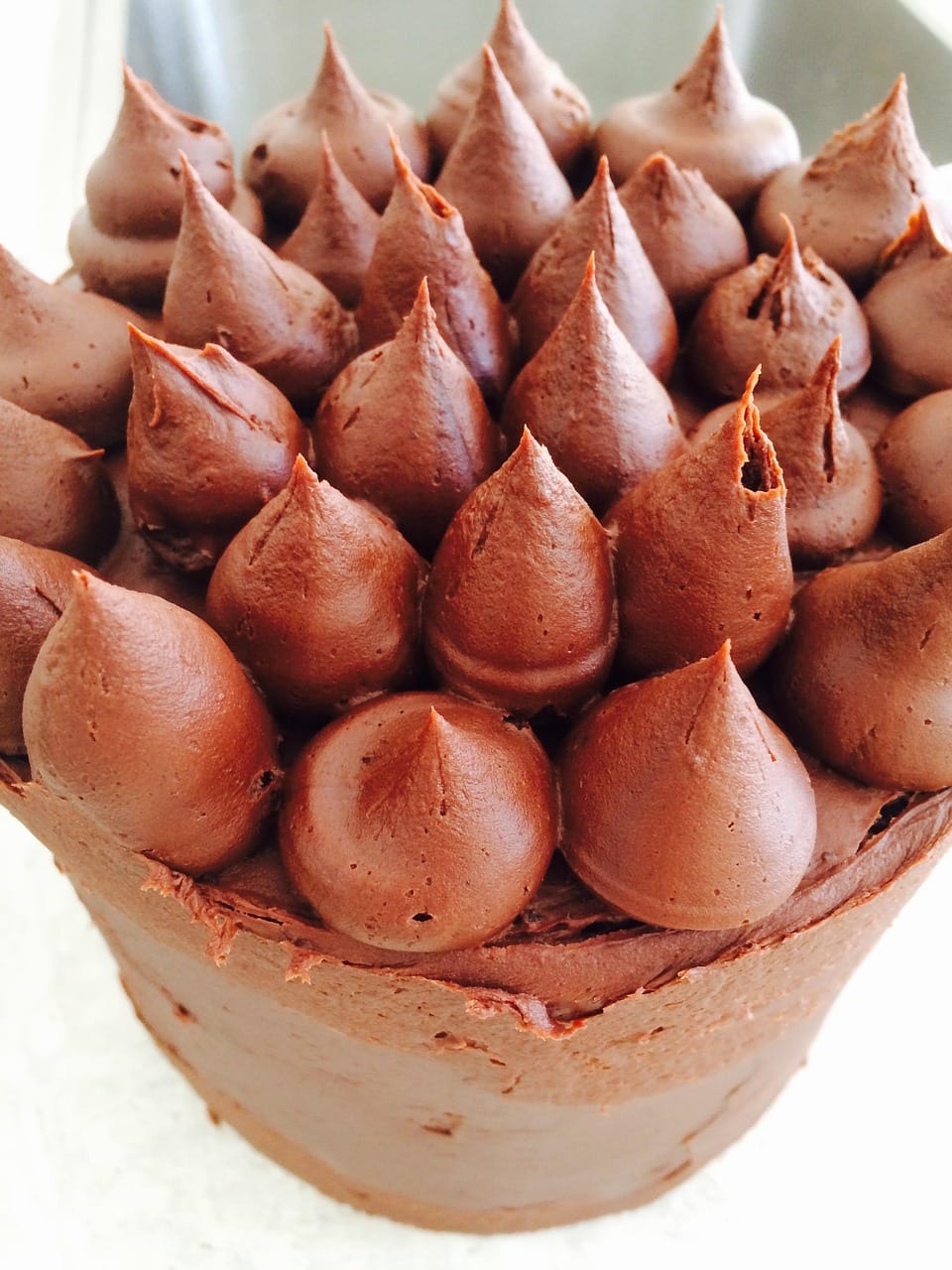 Glossy chocolate ganache being poured over a cake