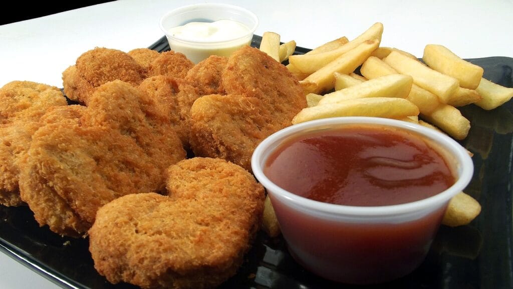 A basket of golden crispy chicken nuggets served with french fries and dipping sauce