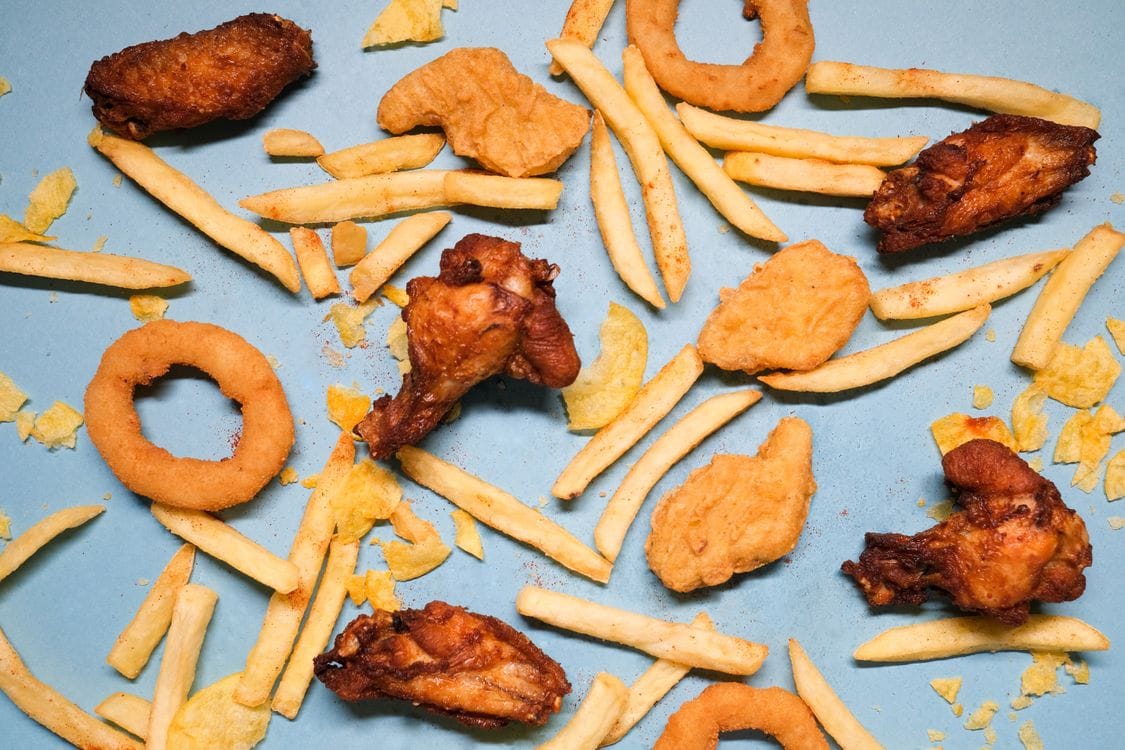 Flat lay of crispy fried chicken pieces and golden french fries with onion rings on a table