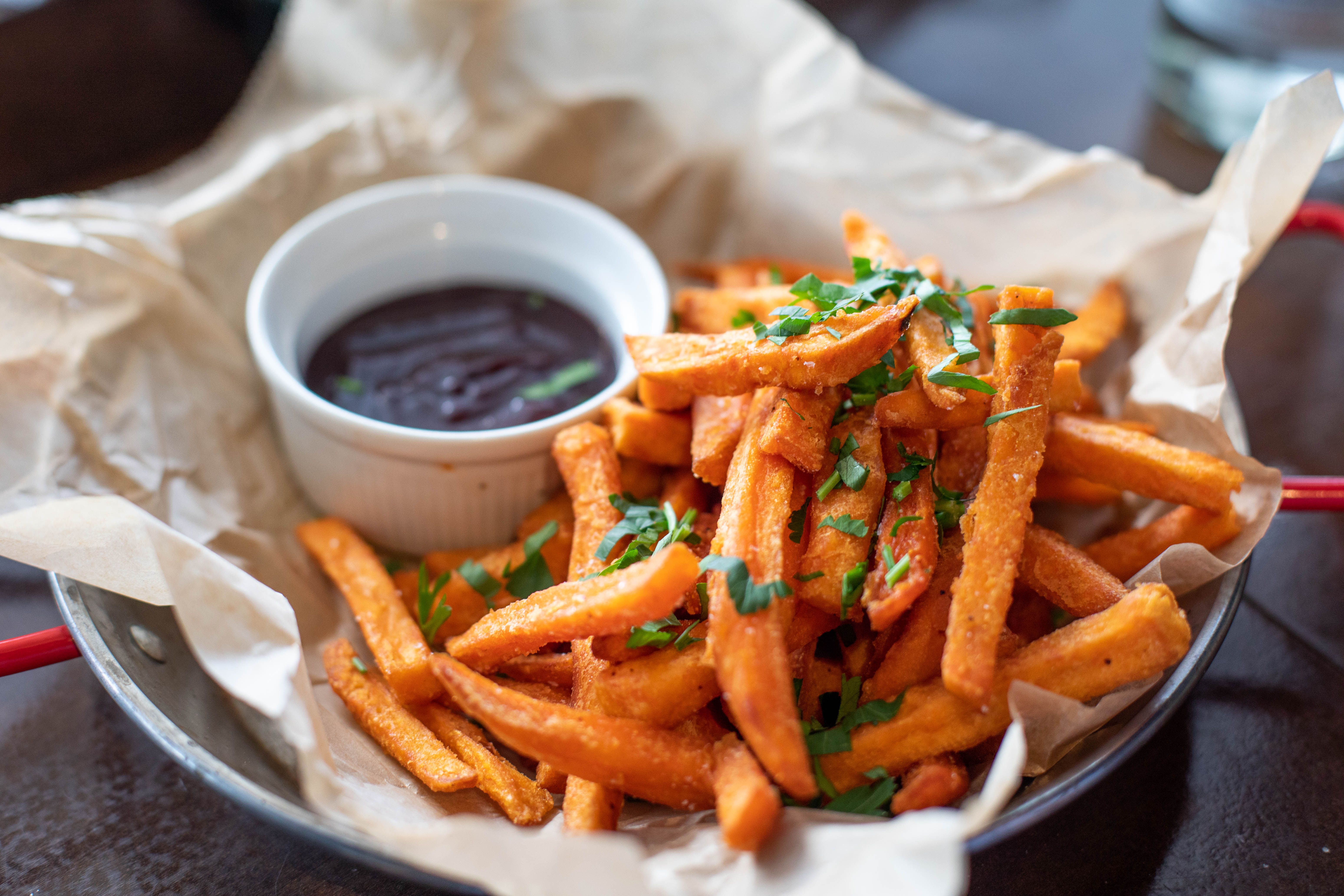Crispy fries garnished with herbs and served with a side of dipping sauce